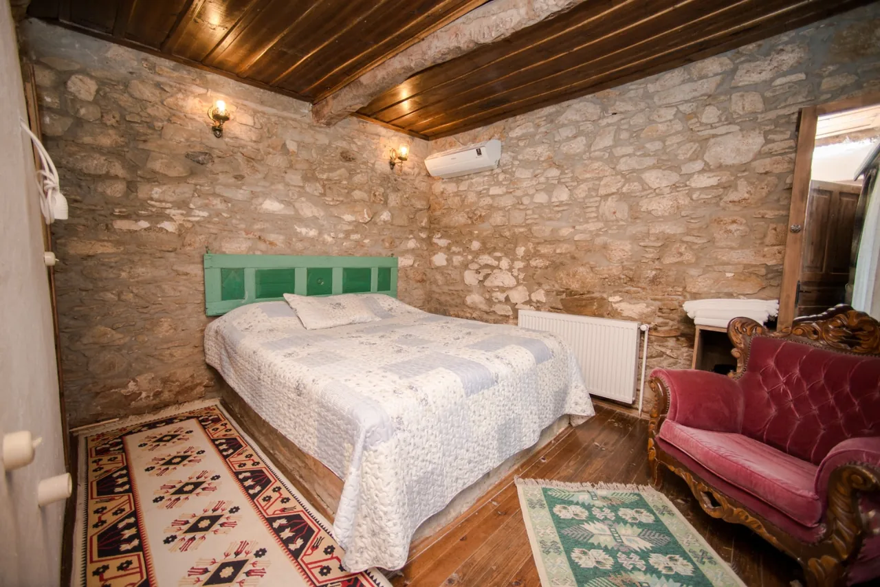 Ceviz Room's stone walls, bed and red armchair