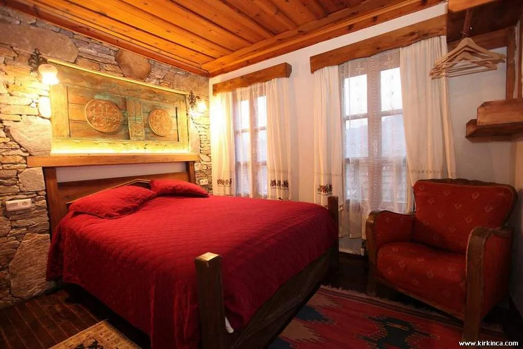 Dilek Room's bed, woven carpet and stone walls