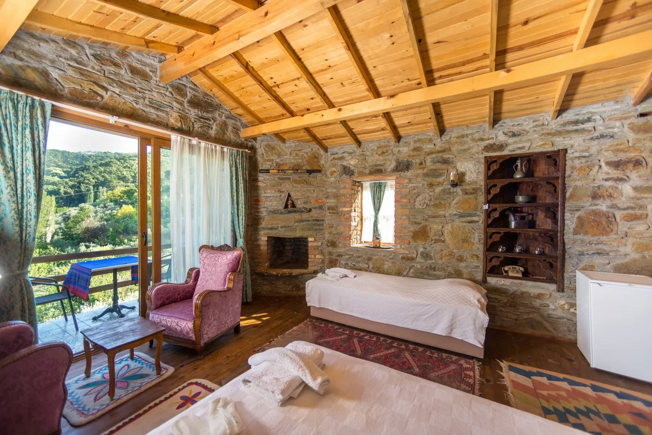 Lavanta House's stone walls, wooden ceiling, white bed and pink armchair