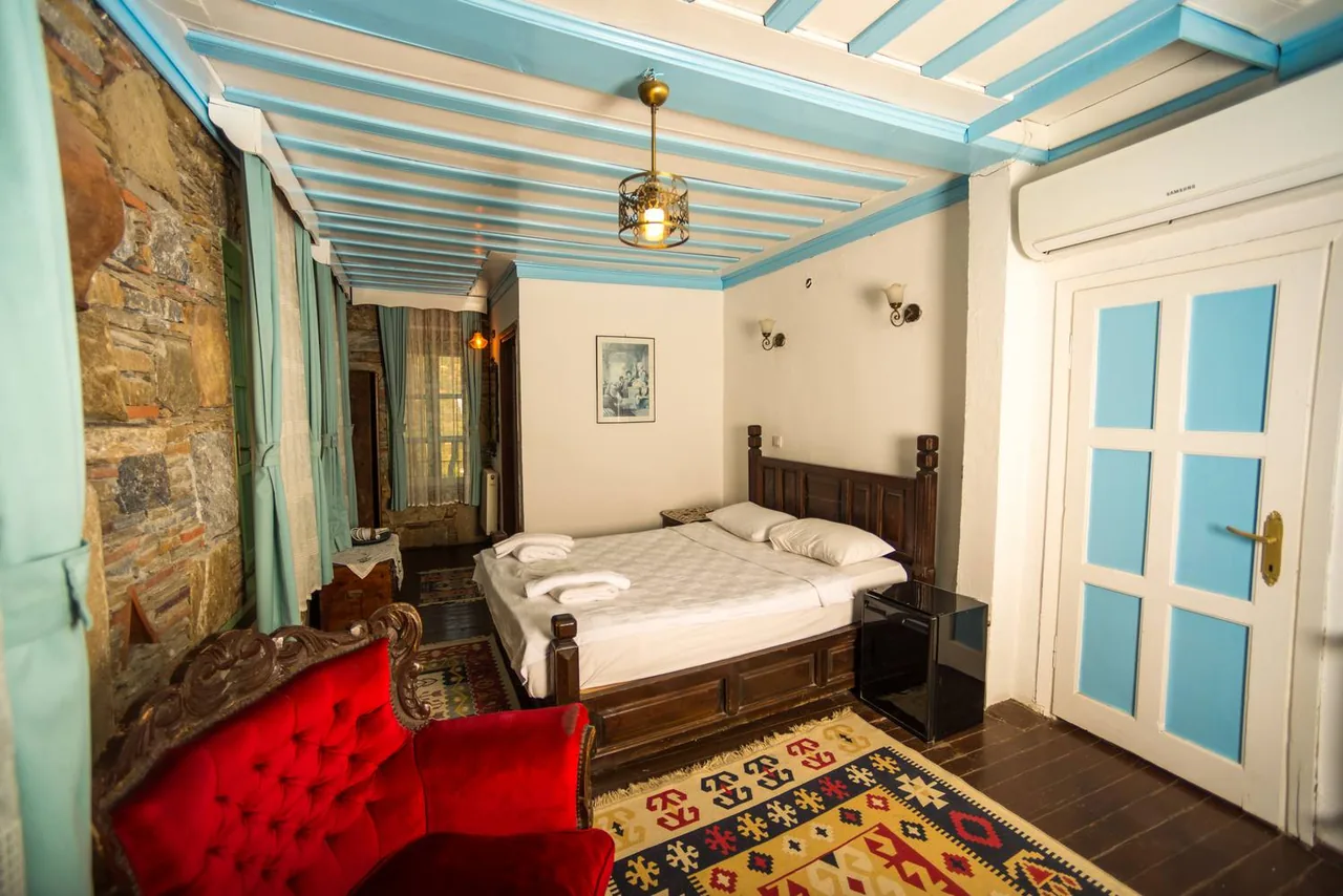 Gül Room's turquoise wooden ceiling, bed and red seating area