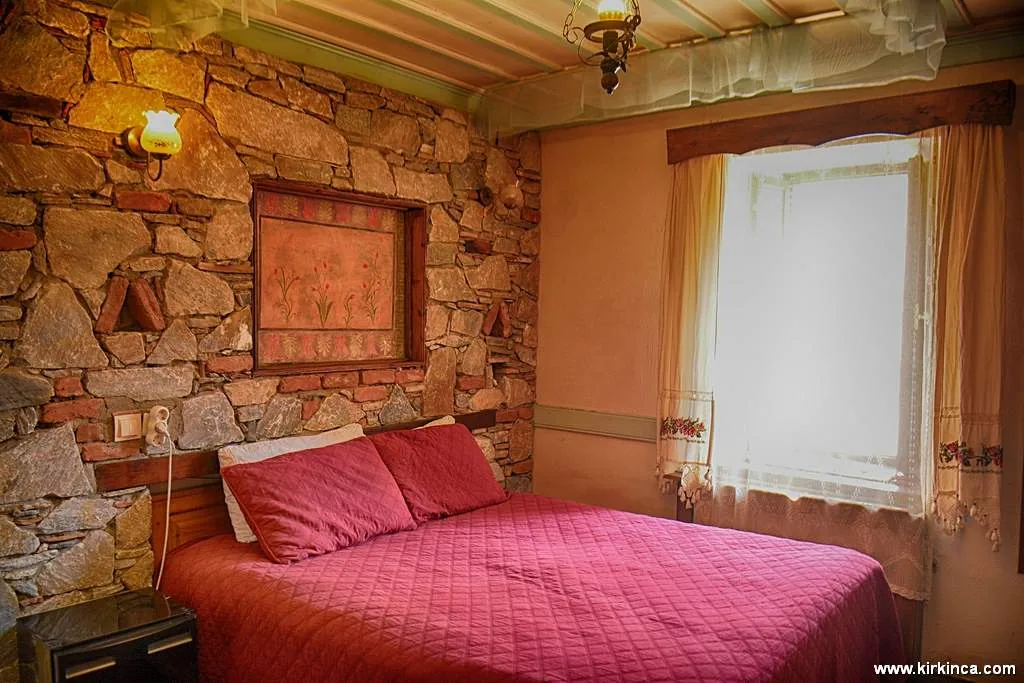 Lale Room's stone walls, wooden ceiling and bed with red covers