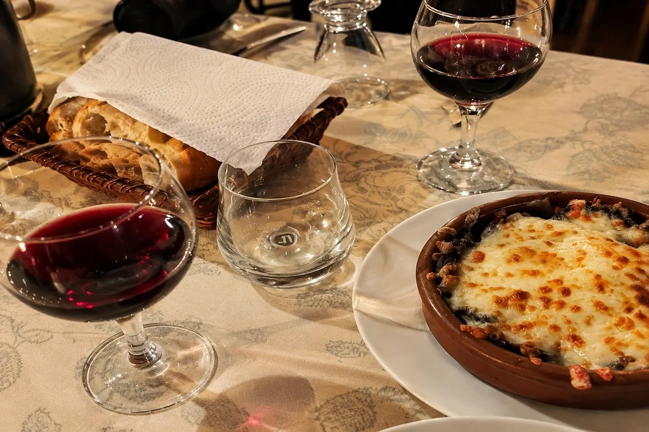 Güveç yemeği, ekmek ve kadehlerle kurulmuş restoran sofrası