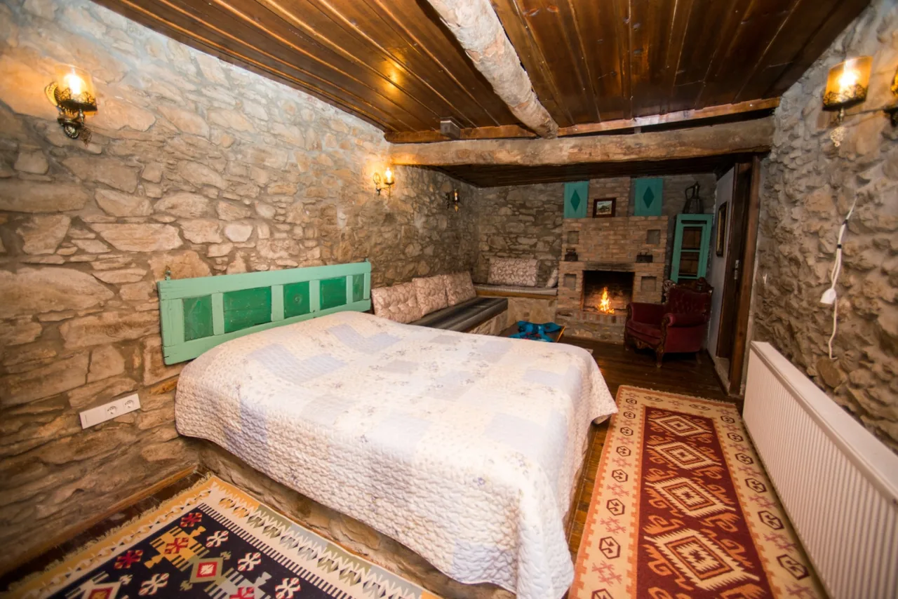Taş Room's stone walls and bed with turquoise headboard